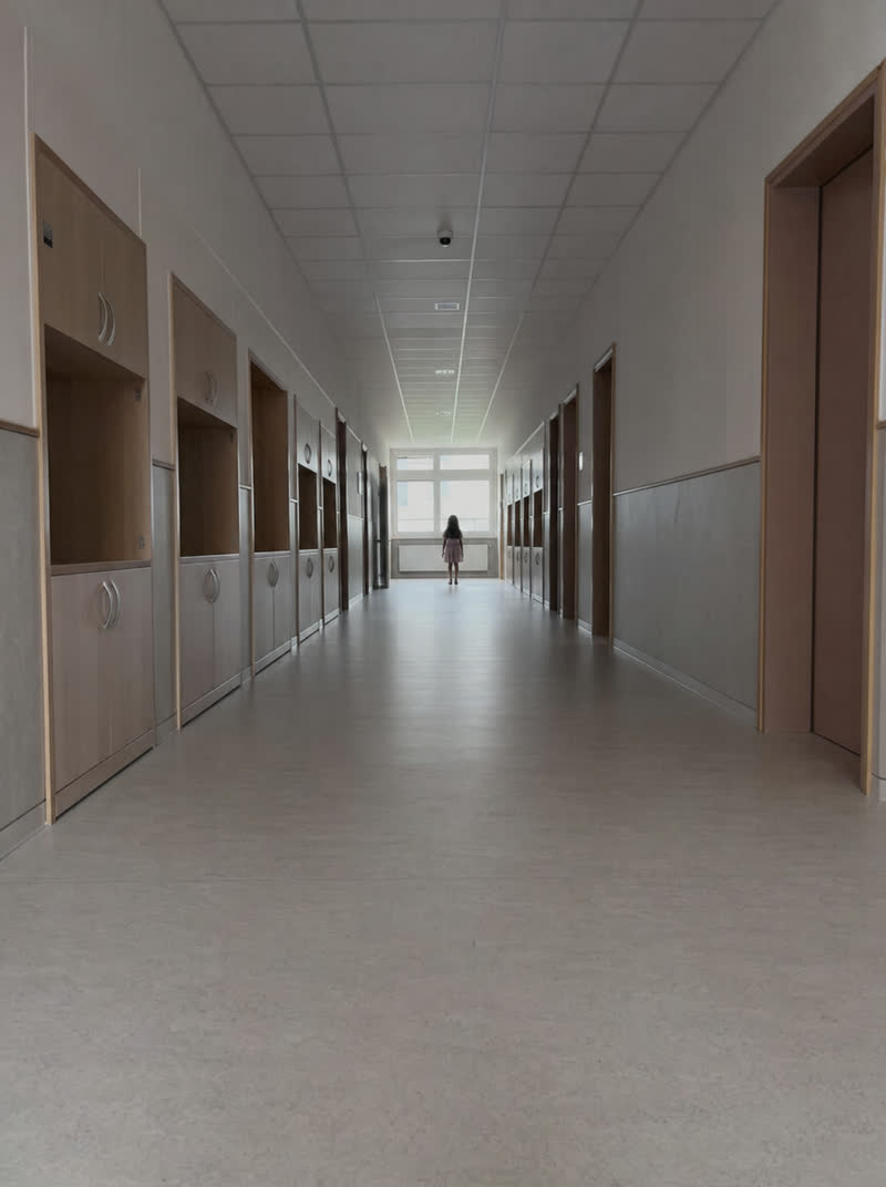 a girl at the end of a school corridor — as shot