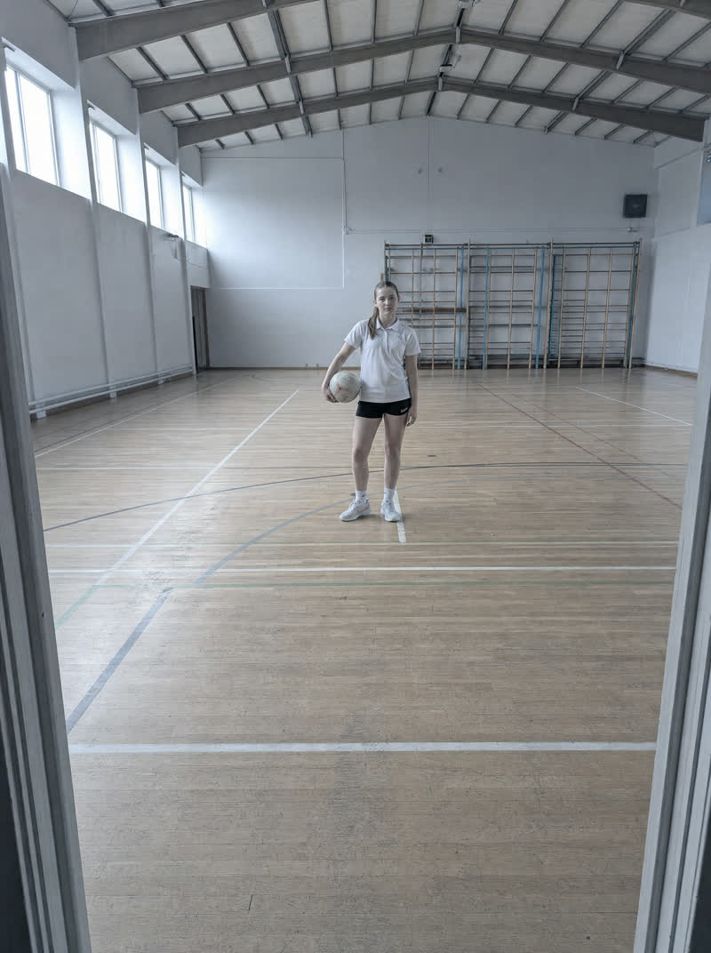 a young athlete alone in a school sports hall — as shot